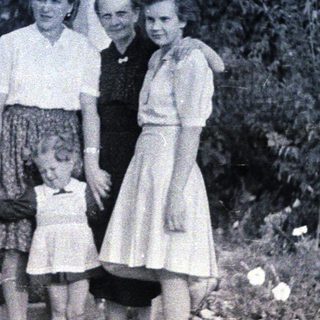 Here's a brief summary of the image: Three women and a young girl standing outdoors.