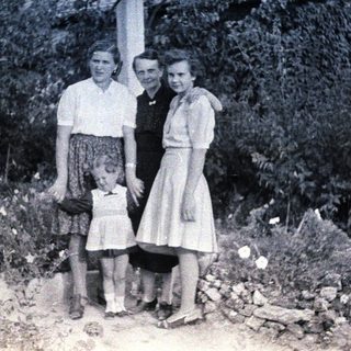 Here's a brief summary of the image: Three women and a young girl standing outdoors.