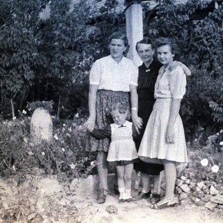 Here's a brief summary of the image: Three women and a young girl standing outdoors.