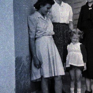 Three women and a young girl stand outside a building.