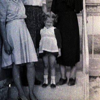 Three women and a young girl stand outside a building.