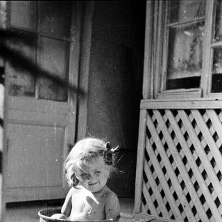 Baby sitting in a bucket outdoors.