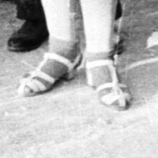 Girl with doll stands with three women outside a house.