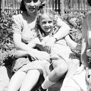 Three young women sitting outdoors in a garden scene.