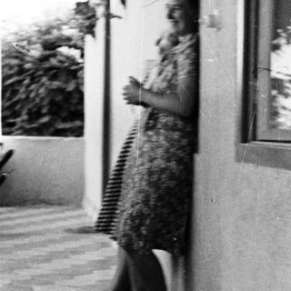 Woman stands on a tiled patio with plants nearby.