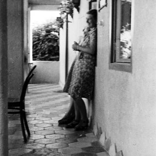 Woman stands on a tiled patio with plants nearby.