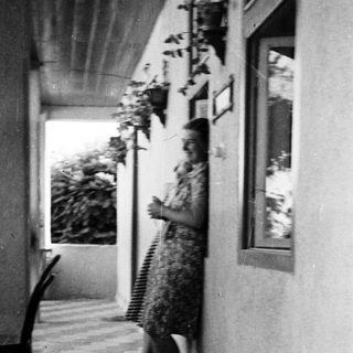 Woman stands on a tiled patio with plants nearby.