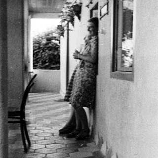 Woman stands on a tiled patio with plants nearby.