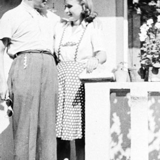 Couple stands on steps, a child nearby, vintage style.