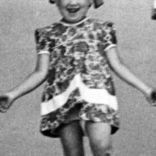 Young girl descends steps, smiling, in vintage clothing.