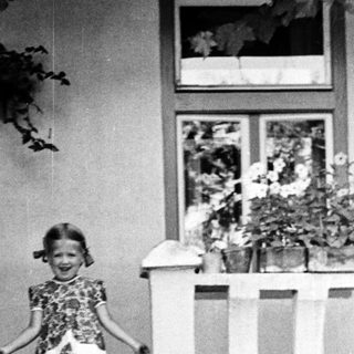 Young girl descends steps, smiling, in vintage clothing.