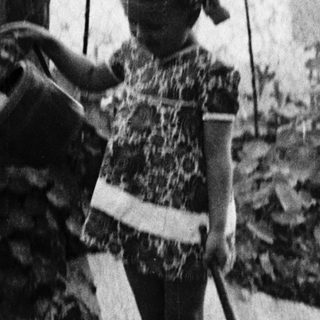 Young girl tending to a garden with a watering can.