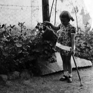 Young girl tending to a garden with a watering can.