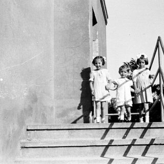 Three young girls stand on a set of concrete stairs.