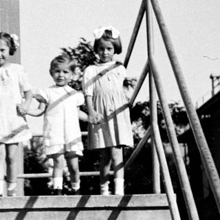 Three young girls stand on a set of concrete stairs.