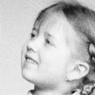 Young girl stands holding a doll and basket.