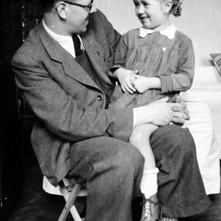 Man sits holding a young girl on his lap.