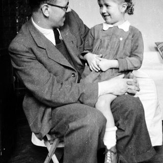 Man sits holding a young girl on his lap.