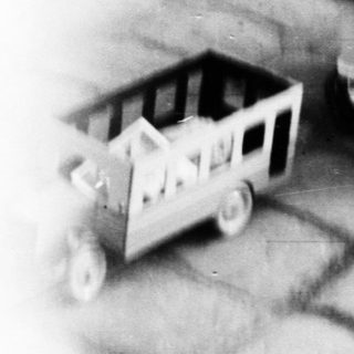 Child plays with a toy cart on a stone path.