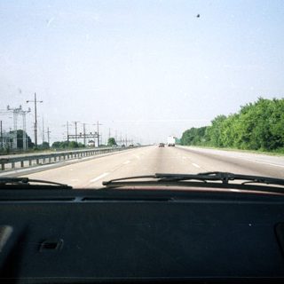 Highway stretches ahead, lined with trees and power lines.