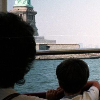Statue of Liberty viewed from a boat, city skyline.