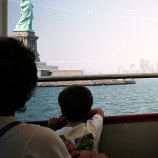 Statue of Liberty viewed from a boat, city skyline.