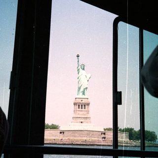 The Statue of Liberty is viewed through a window.