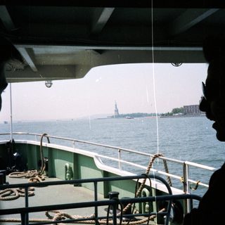 Silhouette overlooking the Statue of Liberty from a boat.