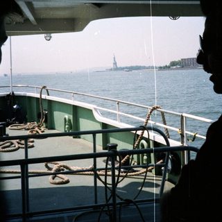 Silhouette overlooking the Statue of Liberty from a boat.