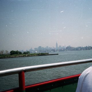 Person looking at the New York City skyline over water.