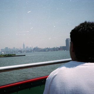 Person looking at the New York City skyline over water.