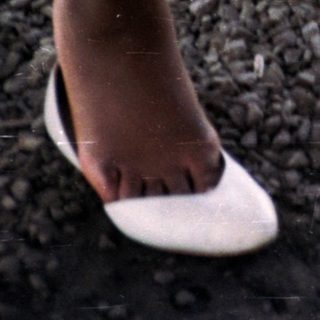Feet in shoes and sneakers on gravel ground.