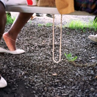 Feet in shoes and sneakers on gravel ground.