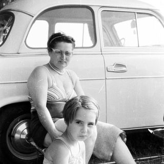 Black and white photo of a girl and woman near a car.