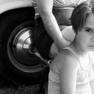 Black and white photo of a girl and woman near a car.