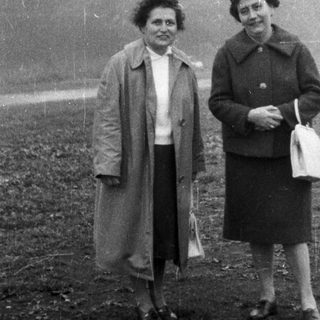 Two women stand outdoors in a black and white photo.