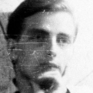 Man seated near vintage radio in a dimly lit room.