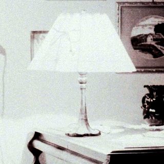 Woman sits at a piano in a vintage-style room.