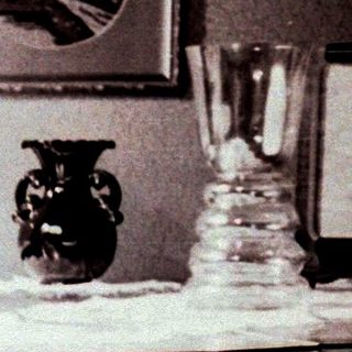 Woman sits at a piano in a vintage-style room.