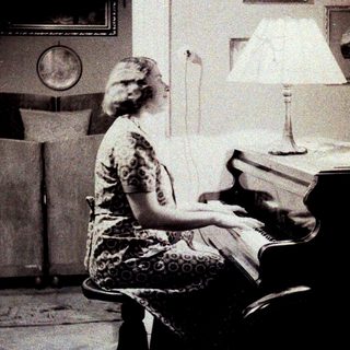 Woman seated at a piano in a vintage interior.