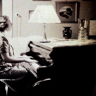 Woman seated at a piano in a vintage interior.
