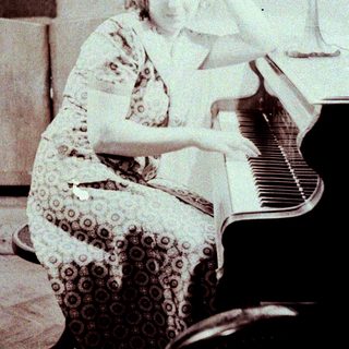 Woman playing piano in vintage patterned dress.