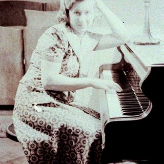 Woman playing piano in vintage patterned dress.