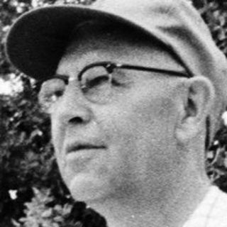 Old man wearing cap and glasses outdoors.