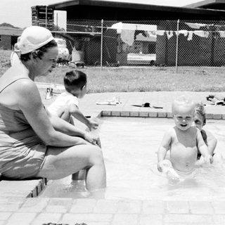 Family enjoying backyard pool on sunny day.