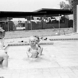 Children playing in a backyard pool.