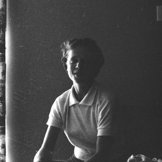 Young woman smiling indoors near window.