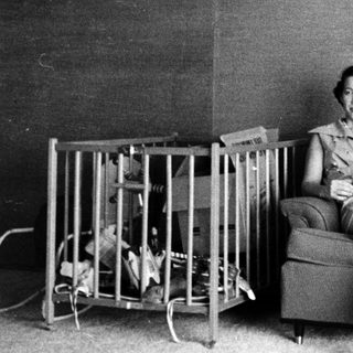 Woman sitting on armchair with baby crib nearby.