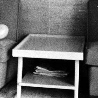 Woman sitting on armchair with baby crib nearby.