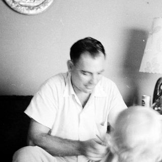 Man cutting hair of seated person indoors.